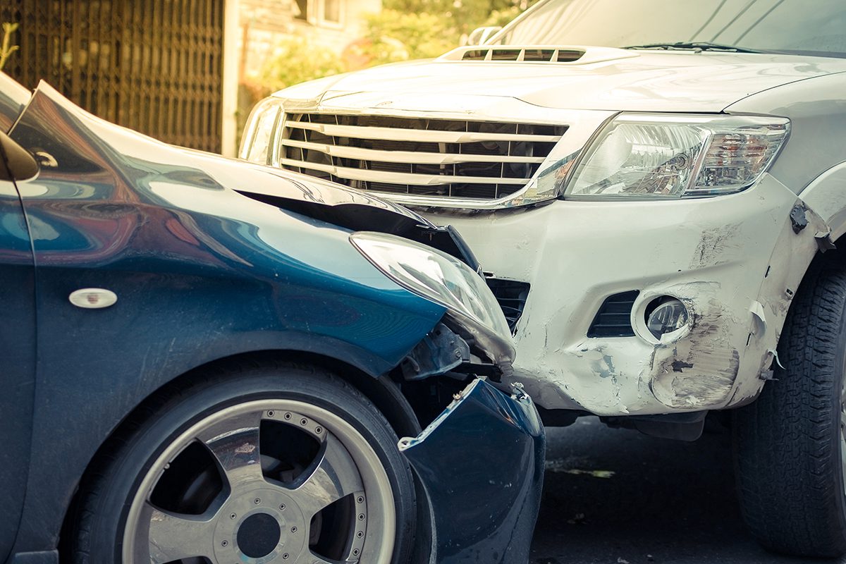 a white and a blue car in a head on collision
